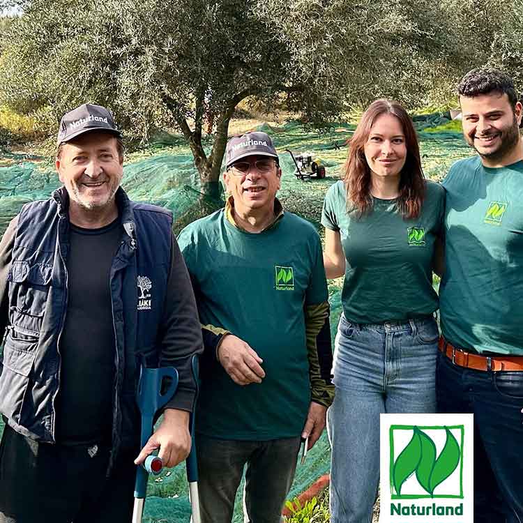 Sparta Team mit Kleinbauern und Naturland Flagge auf Olivenbaumfeld
